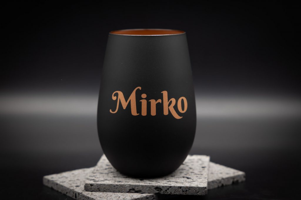 Schwarzer personalisierter Becher aus 3D-Druck mit graviertem Namen Mirko, stilvoll auf grauen, texturierten Steinplatten.